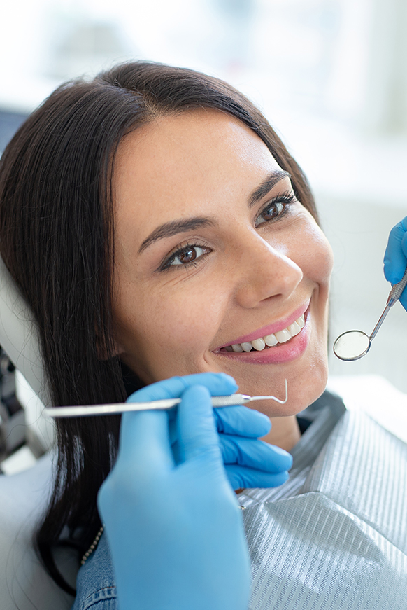 Attractive woman in dental chair smiling before oral surgery in Miami