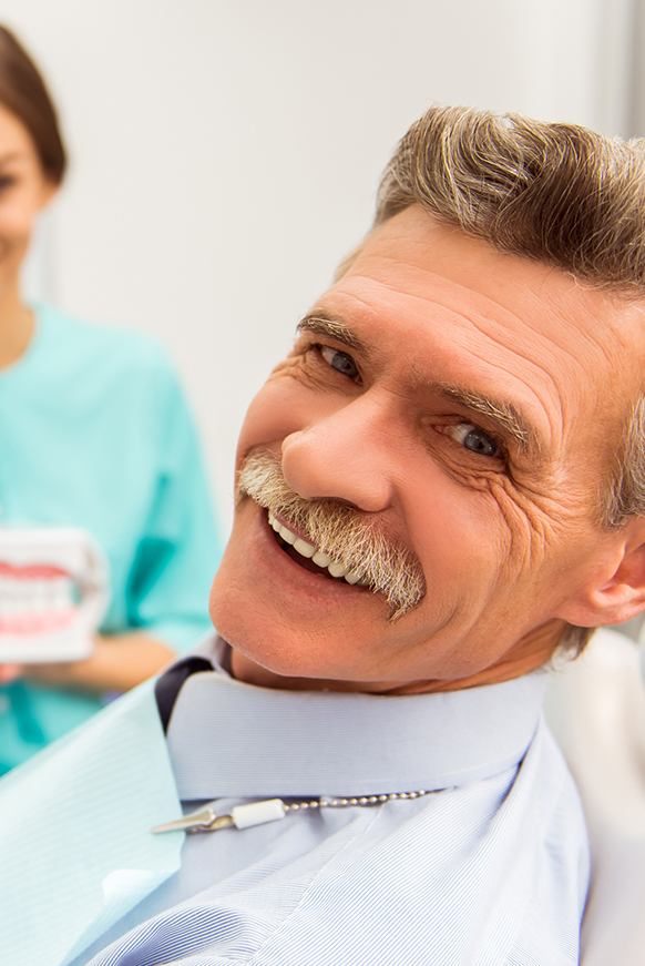 Happy older man with dentist getting a denture fitting.